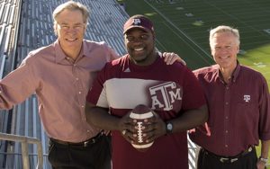 Thornton, Ennis and Morris stand holding a football on the stands at Kyle Field